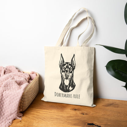 Tote bag with Doberman print and 'Dobermans Rule' text on a wooden surface.