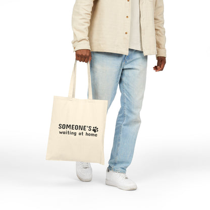 Person holding a tote bag with text on a white background
