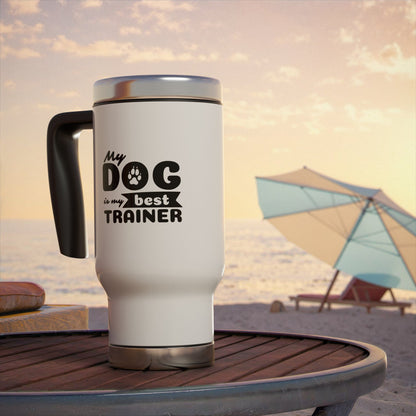 White travel mug with 'My dog is my best trainer' text on a beach setting