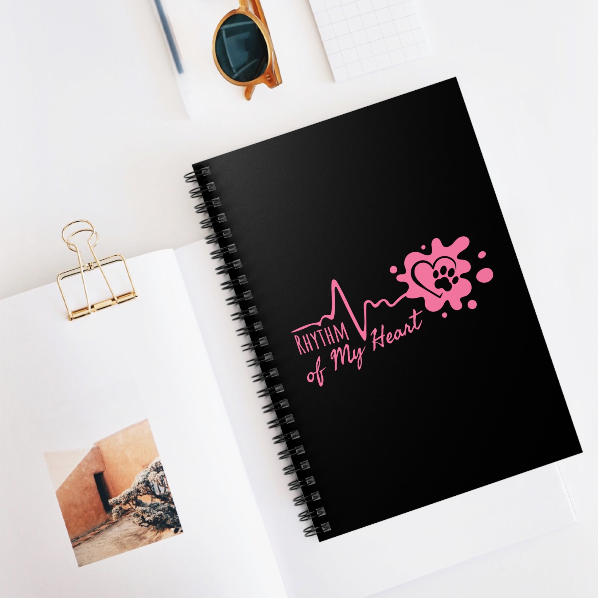 Black notebook with pink design and text on a white surface