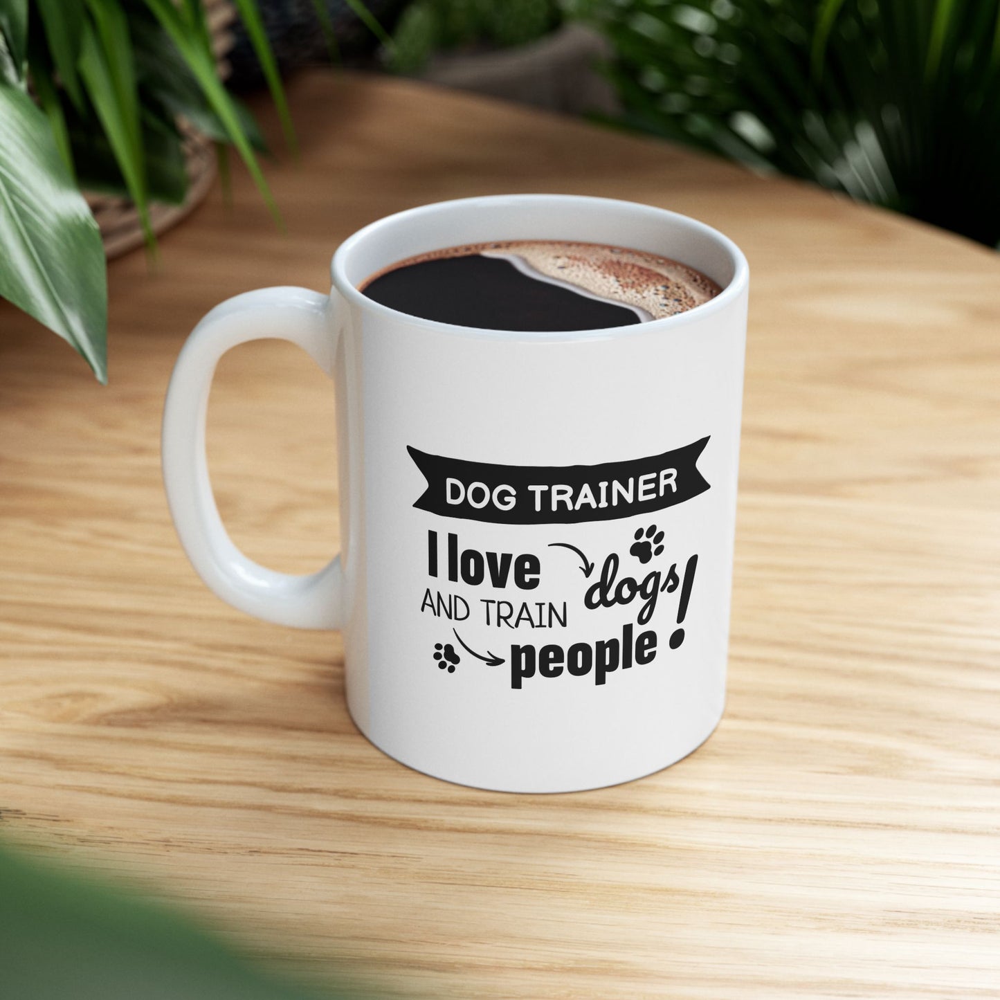 White mug with text 'Dog Trainer I love and train people!' on a wooden table.