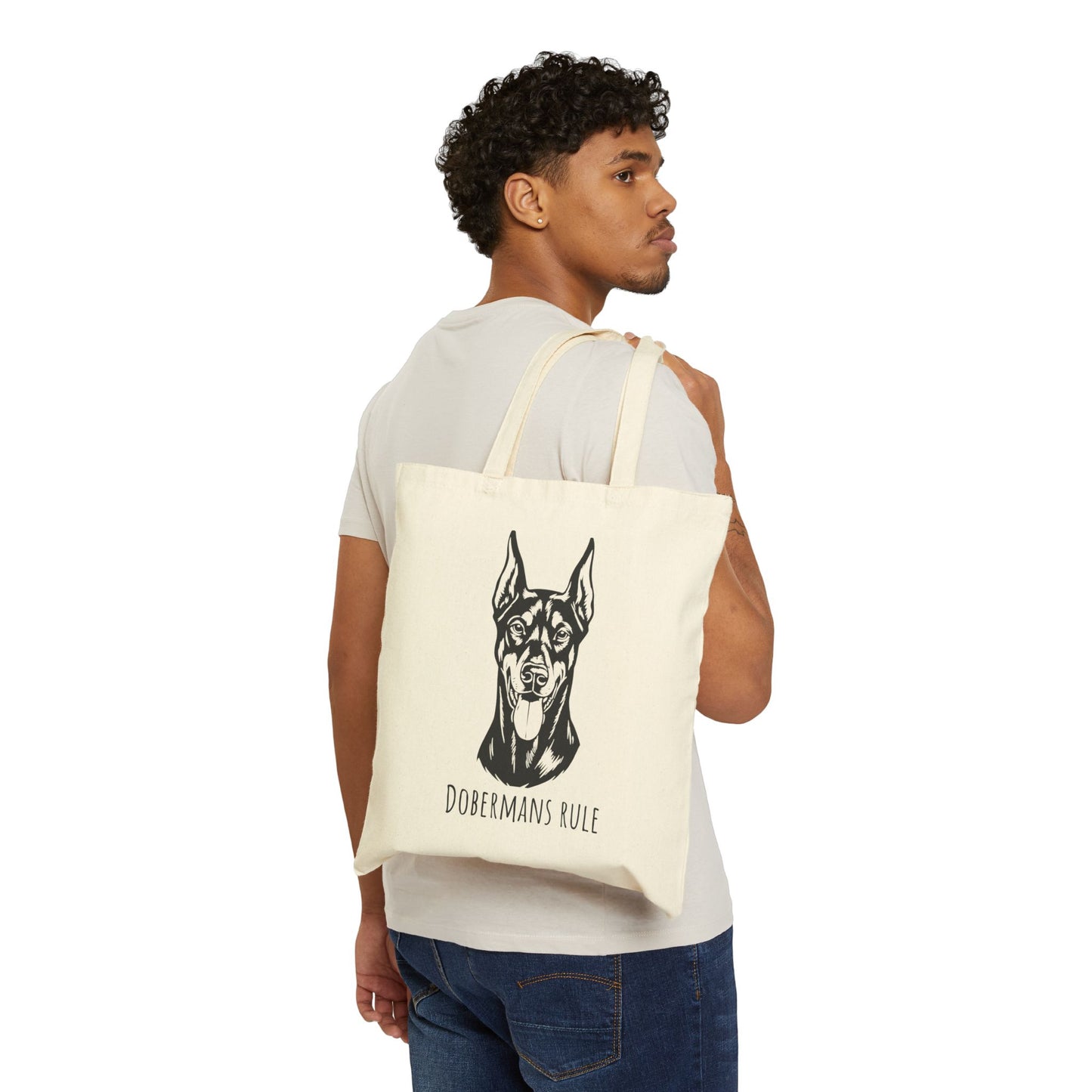 Man carrying a tote bag with a dog illustration and 'Dobermans Rule' text on a white background