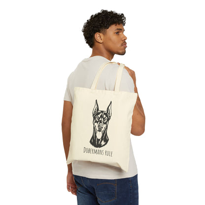 Man carrying a tote bag with a dog illustration and 'Dobermans Rule' text on a white background