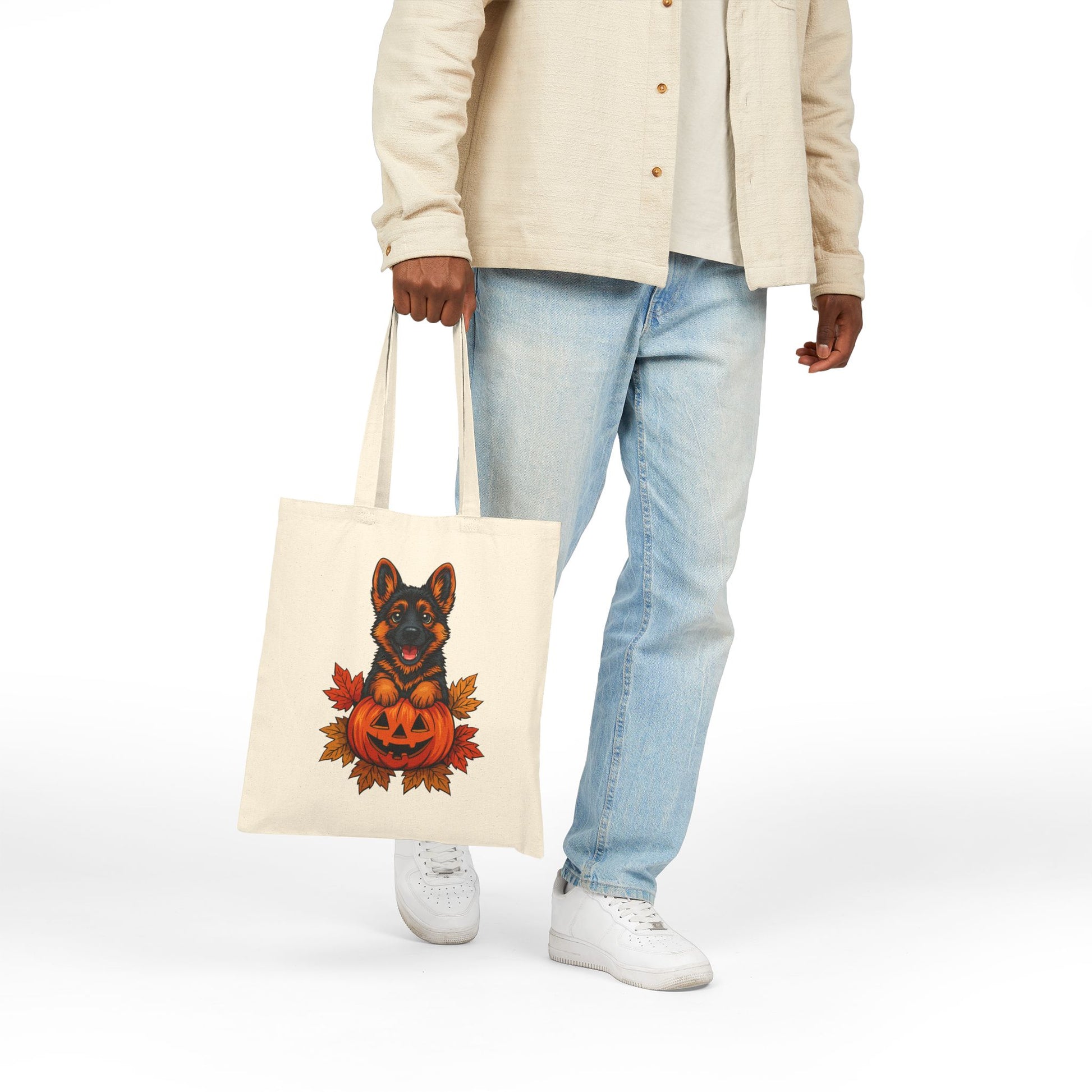 Person holding a tote bag with a dog in a pumpkin design on a white background