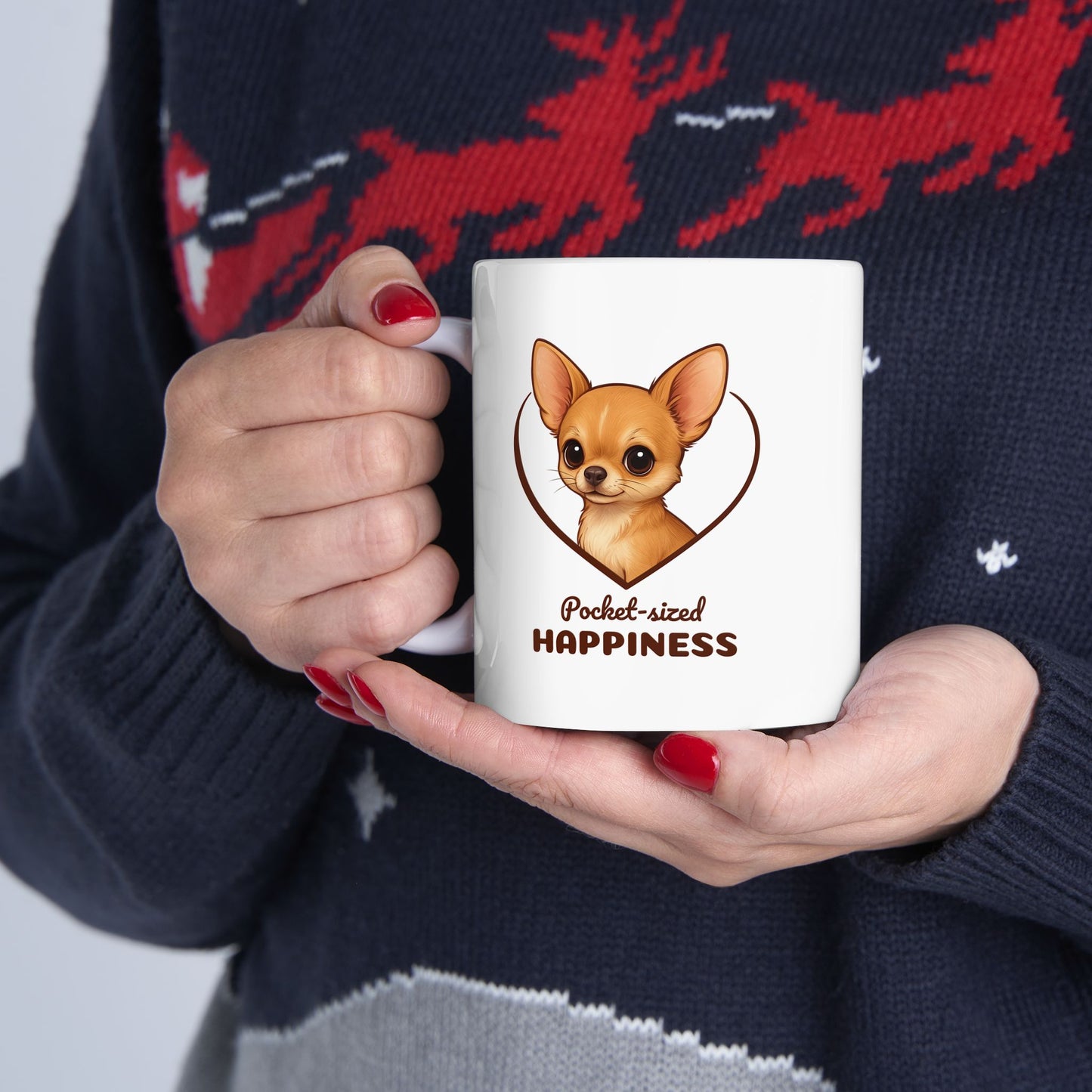 Person holding a mug with a dog illustration and text, wearing a dark sweater with red deer design.
