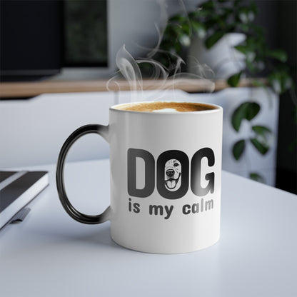 White mug with black handle and 'DOG is my calm' text on a desk with steam rising from it.