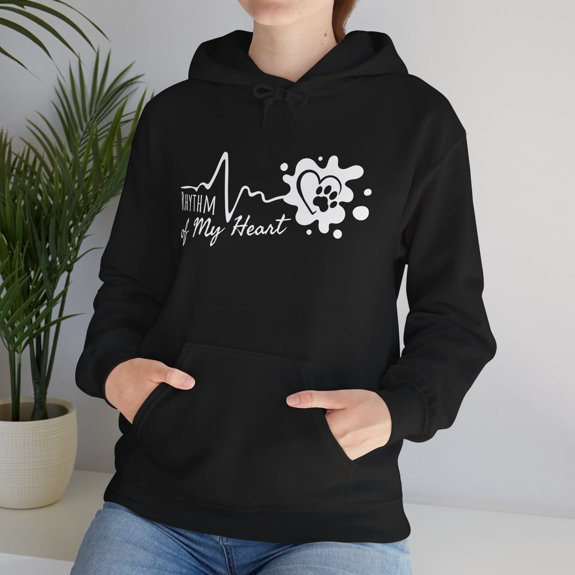 Person wearing a black hoodie with a heart and paw print design, standing indoors.