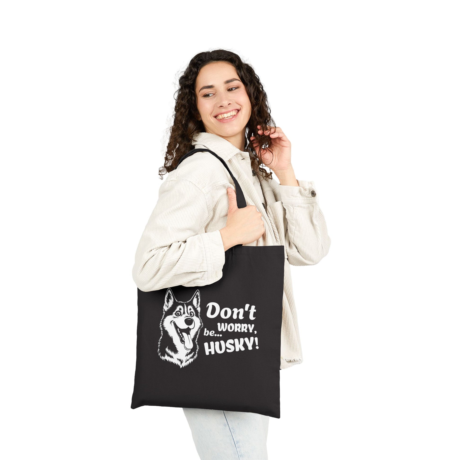 Woman holding a black tote bag with a husky design and text on a white background