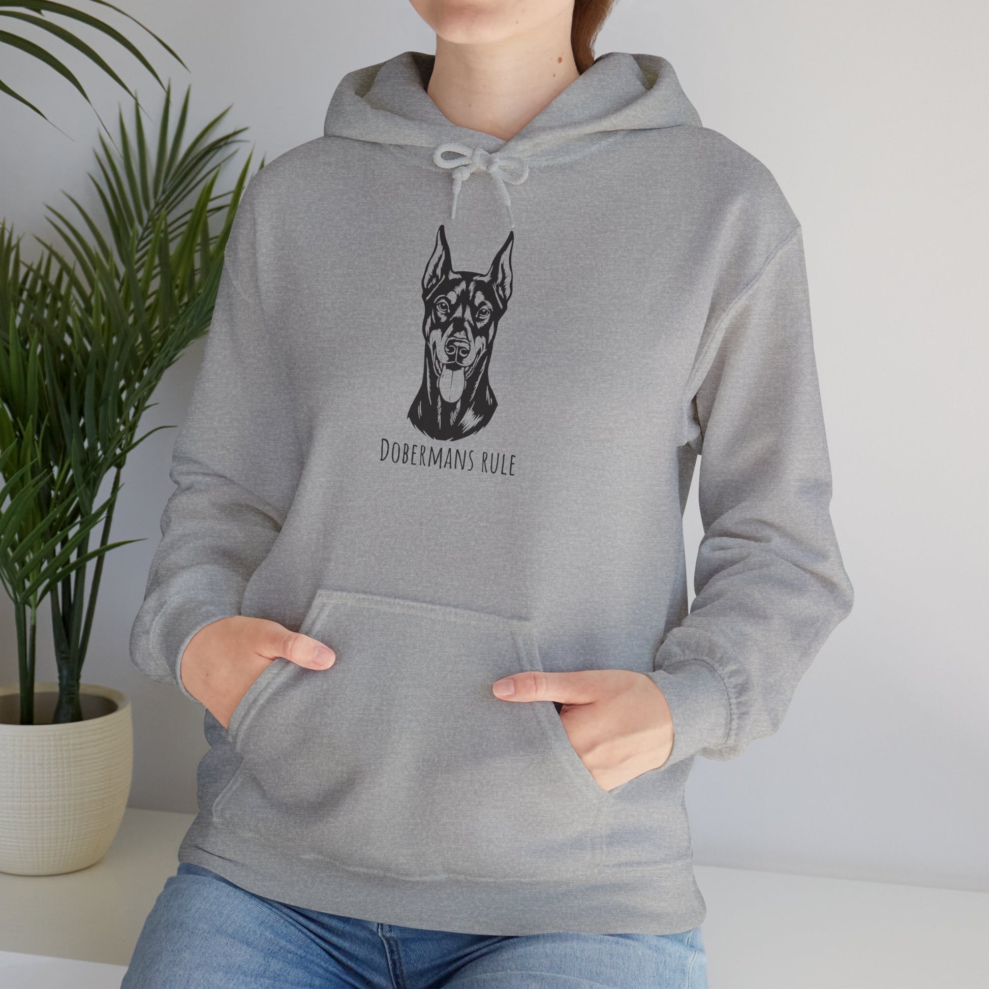 Person wearing a gray hoodie with a dog illustration and 'Dobermans Rule' text, standing indoors.